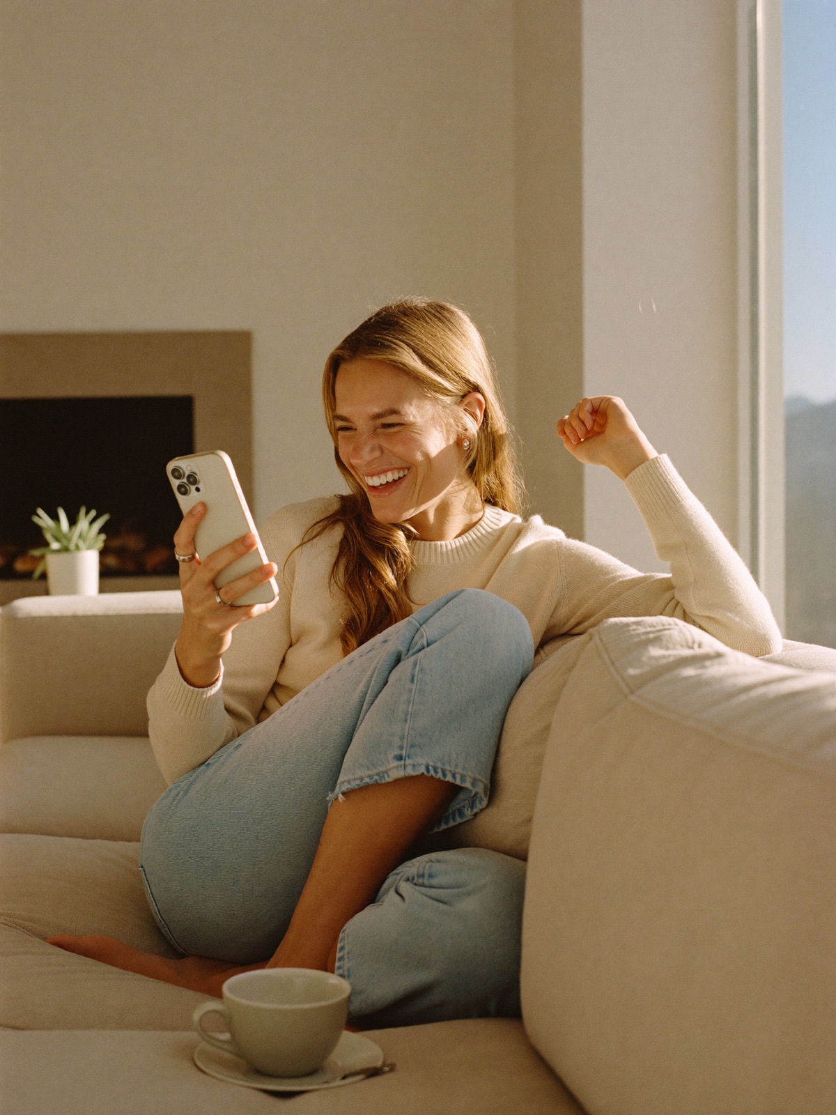 A small business owner relaxing on her sofa, celebrating a new lead on her phone